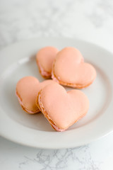 4 Heart Shaped Macarons On A White Plate