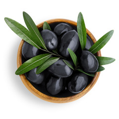 Delicious big black olives with leaves in a wooden bowl, isolated on white background, view from above