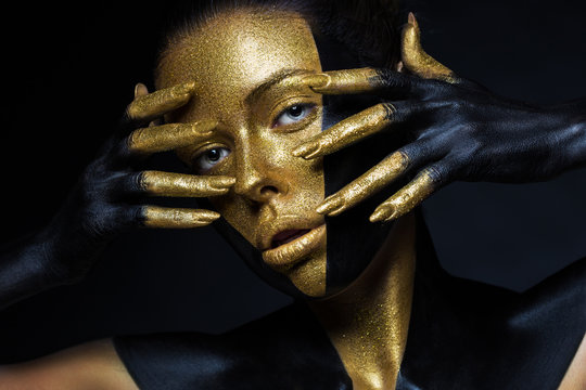 Girl with gold and black paint on her face and body.