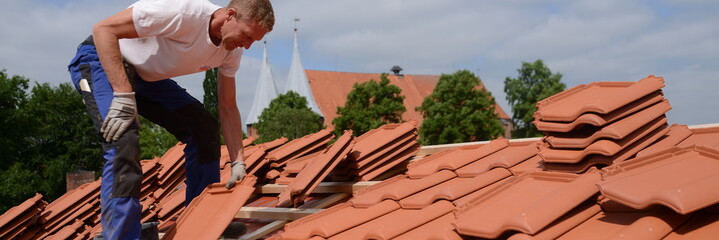 Dachdecker Handwerker in Deutschland: Bauarbeiter Mann draußen mit Dachziegel auf dem Dach,...