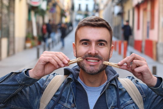 Young male faking a smile with clothespins