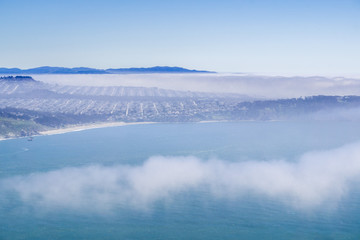 Residential neighborhoods on the Pacific Ocean coastline covered by fog, San Francisco, California