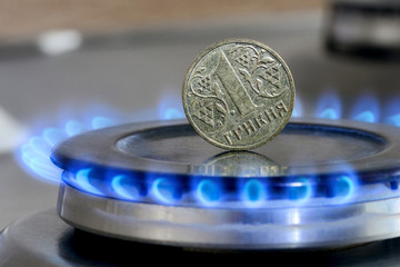 Ukrainian coin hryvnia on gas hob with burning natural gas