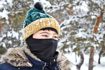 talking on the phone boy in a knitted hat with a bubo and balaclava on a winter walk