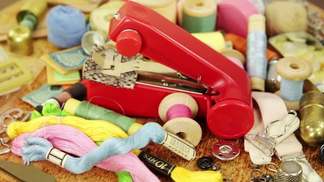 Old portable sewing machinev and various accessories for hand sewing. Bronze and steel thimbles, bronze travel case for sewing accessories, buttons, hooks, needles