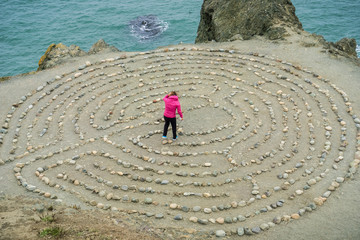 Fototapeta na wymiar Girl playing in a rock maze on the Pacific Ocean coastline, San Francisco, California