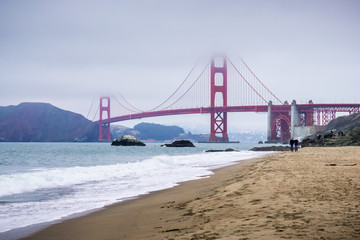 People walking on a sandy beach close to Golden Gate Bridge, San Francisco, California