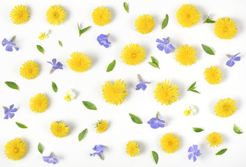 Obraz premium Floral pattern made of yellow dandelion, lilac flowers and leaves isolated on white background. Flat lay. Top view.