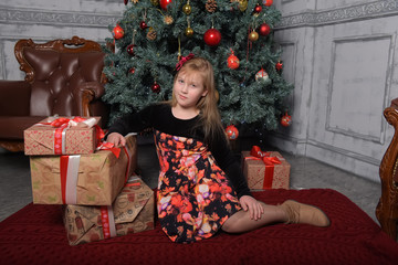 girl blonde child in black with red dress in christmas by the christmas tree