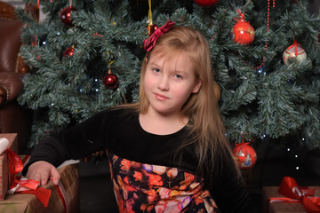 girl blonde child in black with red dress in christmas by the christmas tree