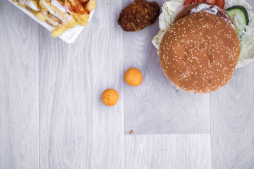 tasty delicious hamburger in box with French fries and vegetable, grey background, wood pattern, light picture, close up of meal, unhealthy fast food option for eating