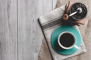 black coffee in a coffee cup with coffee beans and coffee grinder on wooden table.  top view
