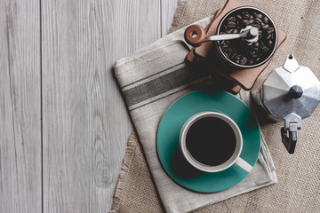 black coffee in a coffee cup with coffee beans and coffee grinder on wooden table.  top view