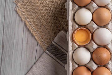 Chicken eggs and egg yolk in carton box on wooden table.