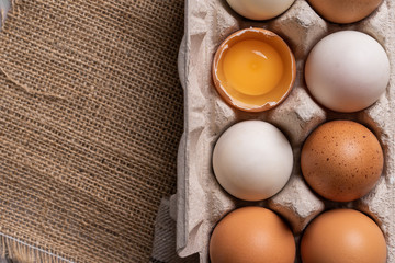 Chicken eggs and egg yolk in carton box on wooden table.