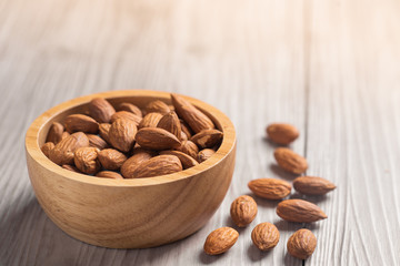Almonds in a wooden bowl with wooden background 