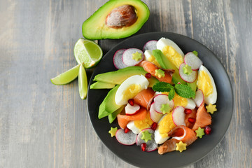 Salad with organic avocado and with salmon, eggs and radish. Decorated with mint leaf and pomegranate. Healthy lunch, vegetarian food, diet dish. food for weight loss. Selective focus and copy space