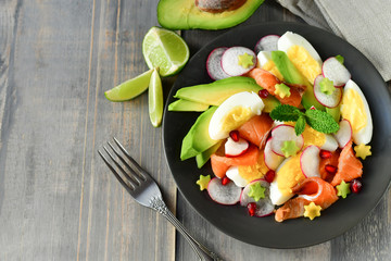 Salad with organic avocado and with salmon, eggs and radish. Decorated with mint leaf and pomegranate. Healthy lunch, vegetarian food, diet dish. food for weight loss. Selective focus and copy space