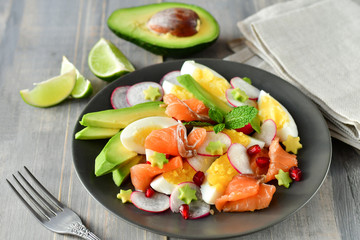 Salad with organic avocado and with salmon, eggs and radish. Decorated with mint leaf and pomegranate. Healthy lunch, vegetarian food, diet dish. food for weight loss. Selective focus and copy space