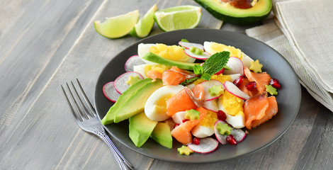 Salad with organic avocado and with salmon, eggs and radish. Decorated with mint leaf and pomegranate. Healthy lunch, vegetarian food, diet dish. food for weight loss. Selective focus and copy space