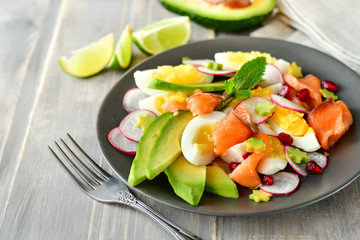 Salad with organic avocado and with salmon, eggs and radish. Decorated with mint leaf and pomegranate. Healthy lunch, vegetarian food, diet dish. food for weight loss. Selective focus and copy space