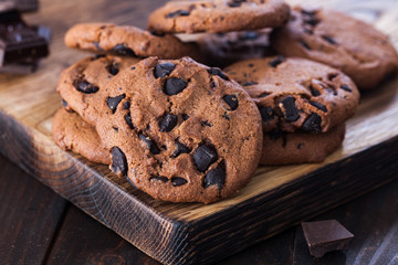 Homemade chocolate cookies on dark old wooden table. Chocolate chips cookies shot.