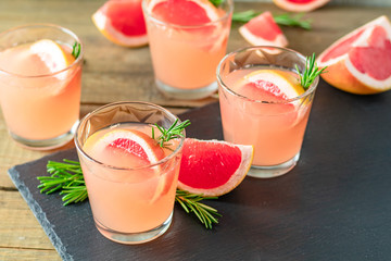 Fresh pink alcoholic cocktail with grapefruit, ice and rosemary