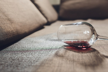 Red wine spilled on a grey couch sofa.