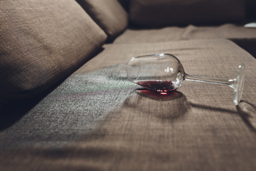 Red wine spilled on a grey couch sofa.