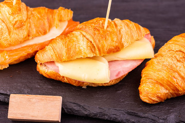 Croissant with ham and cheese with a wooden inscription
