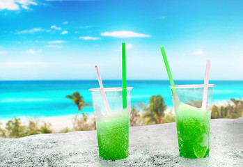 Two apple green drift-ice with straw on the beach. In the background is blue sky, palms, sea nd sandy beach. This is situated in tropical resort in Asia © Jana