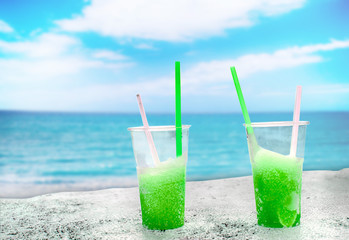 Two apple green drift-ice with straw on the beach. In the background is blue sky, palms, sea nd sandy beach. This is situated in tropical resort in Asia © Jana