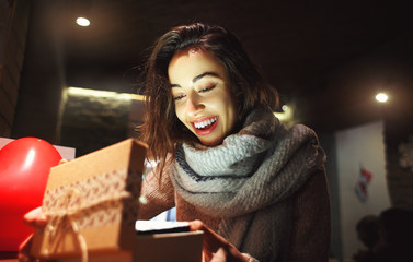 happy surprised beautiful woman is opening a gift box in cafe at Valentines Day