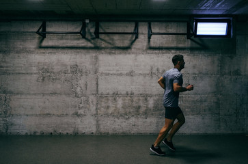 Fototapeta premium Sporty man in sportswear running indoors. Stop saying I wish, start saying I will.