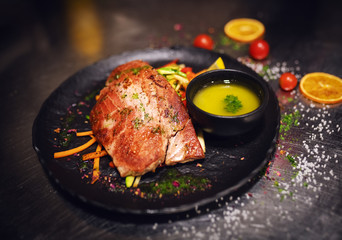 Close up of delicious tuna steak on crunchy vegetables. On plate little bowl of soup, too.