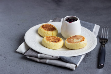 Cottage cheese pancakes or fritters with blueberry sauce and mint. Traditional Ukrainian and Russian cuisine. Syrniki. Healthy and diet breakfast.