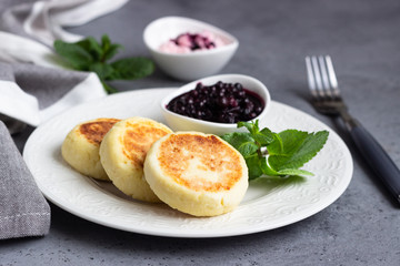 Cottage cheese pancakes or fritters with blueberry sauce and mint. Traditional Ukrainian and Russian cuisine. Syrniki. Healthy and diet breakfast.