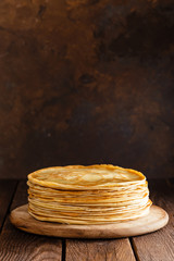 Homemade thin crepes with honey, pancakes on wooden rustic background
