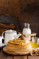 Homemade thin crepes with honey, pancakes on wooden rustic background