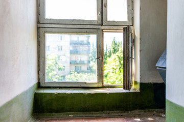 Inside stairway corridor in old Soviet apartment building in Ukraine, in summer, nobody, run-down open window, interior floor with trash chute