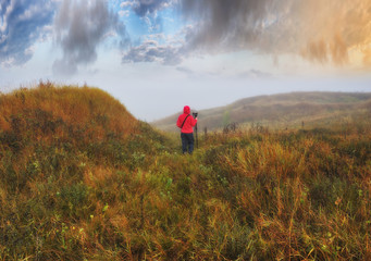 tourist on a hill above the picturesque river. woman is meditating on nature. autumn morning