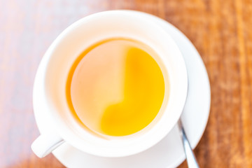 Flat top high angle closeup of one white cup on plate of green or oolong tea in breakfast brunch outdoor cafe restaurant outside wooden table with orange colorful vibrant color