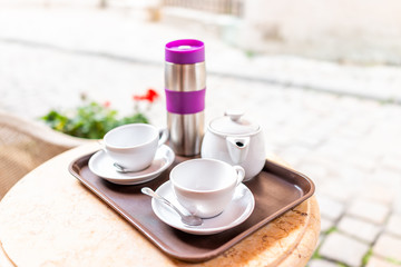 Closeup of two white cups of coffee or tea in breakfast brunch outdoor cafe restaurant outside table with sunny day, thermos and teapot pot
