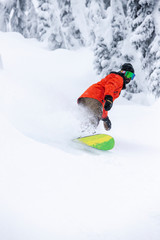 Man Wearing Orange Jacket Carving Snowboard in Fresh Powder Snow