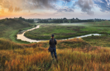 tourist on a hill above the picturesque river. woman is meditating on nature. autumn morning