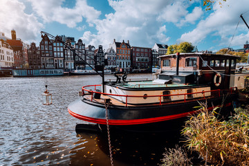 Fototapeta premium Houseboat and traditional leaning buildings along the canal in Amsterdam