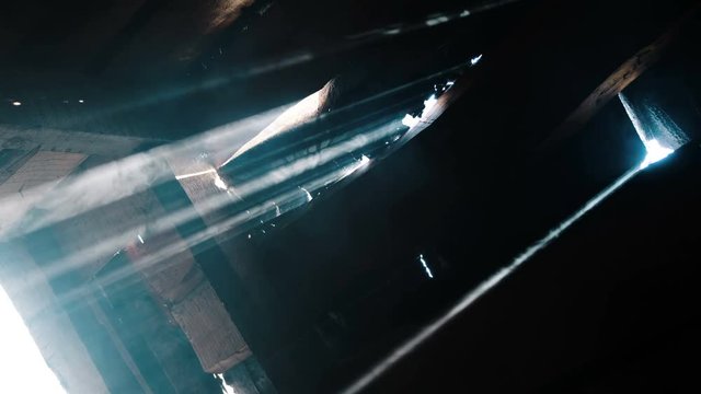 Suns rays shine through the gap in the wooden door, the smoke in the dark building glows