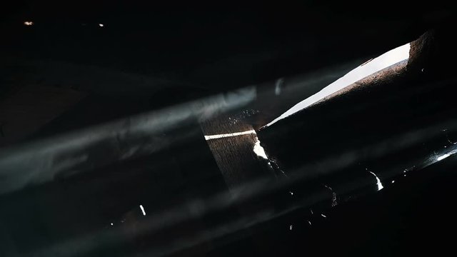 Smoke glows in a dark wooden shed. Suns rays shine through the cracks, slow motion