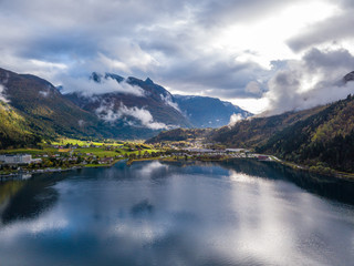 Fototapeta na wymiar Drone Photo of the Cityscape of Leon in Norway with the Innvikfjorden Fjord in the Foreground and the Clouds Covering big Mountains in the Background