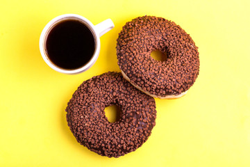 Two delicious chocolate donuts with sprinkle and cup of coffee